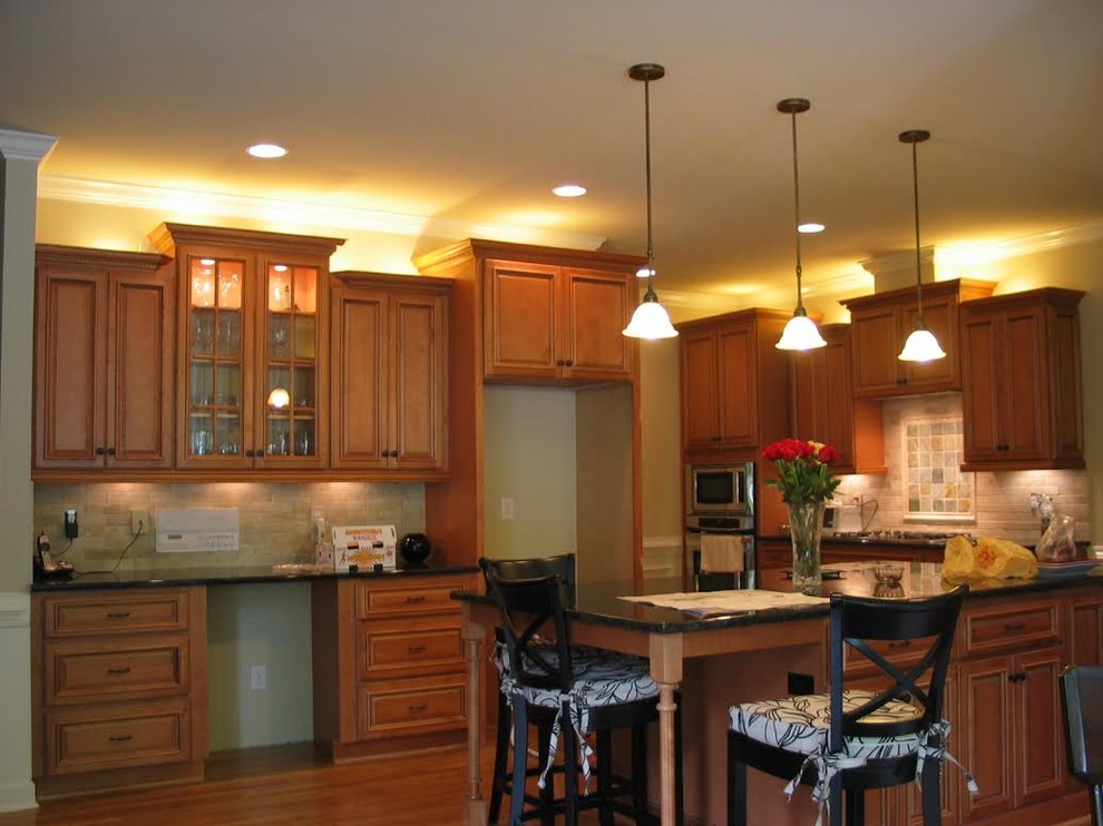 Inspiration for a large timeless u-shaped medium tone wood floor eat-in kitchen remodel in St Louis with raised-panel cabinets, medium tone wood cabinets, granite countertops, beige backsplash, stone tile backsplash, stainless steel appliances and a peninsula