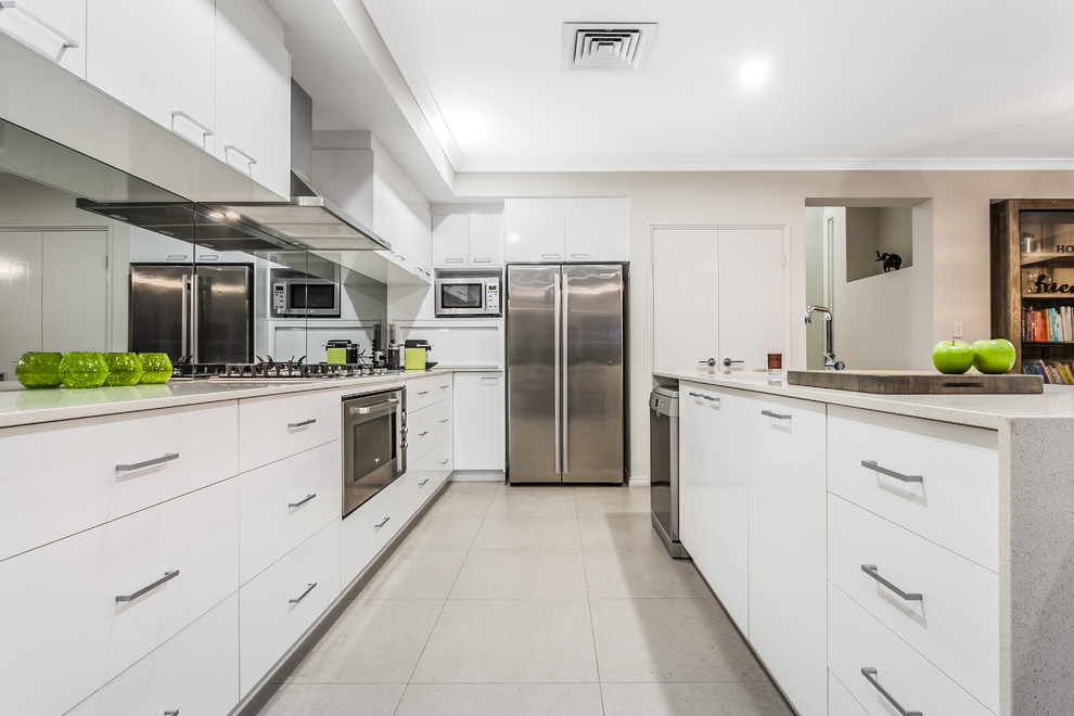Moderne Küche mit flächenbündigen Schrankfronten, weißen Schränken, Rückwand aus Spiegelfliesen, Küchengeräten aus Edelstahl und Halbinsel in Perth
