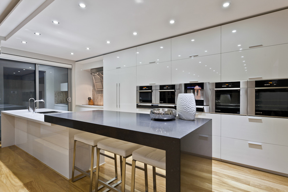 Immagine di una cucina parallela design con ante lisce, ante bianche, paraspruzzi grigio e elettrodomestici da incasso