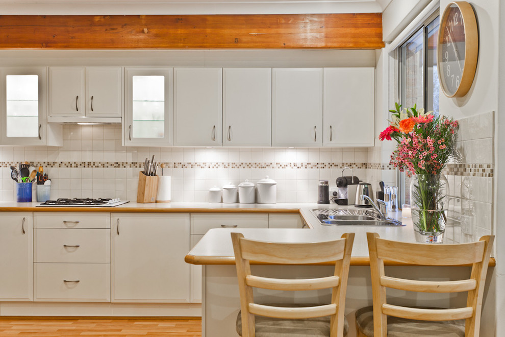 Foto di una cucina design con ante con bugna sagomata, ante bianche, top in laminato, paraspruzzi bianco, paraspruzzi con piastrelle a mosaico e lavello da incasso