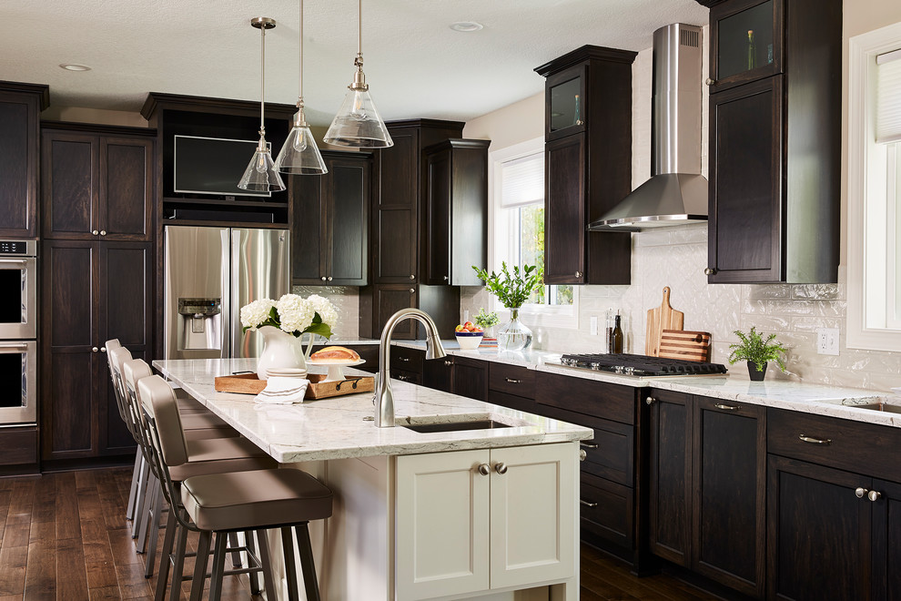Inspiration for a large timeless l-shaped dark wood floor and brown floor eat-in kitchen remodel in Minneapolis with an undermount sink, recessed-panel cabinets, dark wood cabinets, granite countertops, white backsplash, subway tile backsplash, stainless steel appliances, an island and white countertops