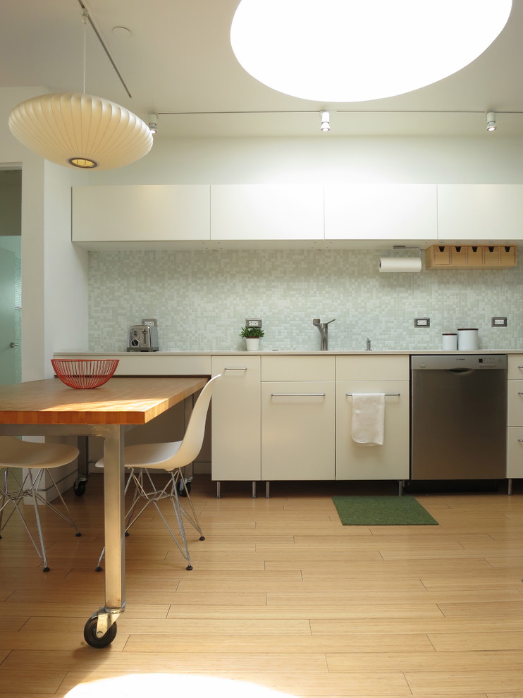Bild på ett litet minimalistiskt kök, med stänkskydd i mosaik, en undermonterad diskho, släta luckor, vita skåp, bänkskiva i kvarts, vitt stänkskydd, rostfria vitvaror, mellanmörkt trägolv och en halv köksö