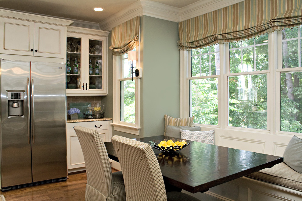 Ejemplo de cocina comedor clásica con armarios con paneles empotrados, puertas de armario blancas y electrodomésticos de acero inoxidable
