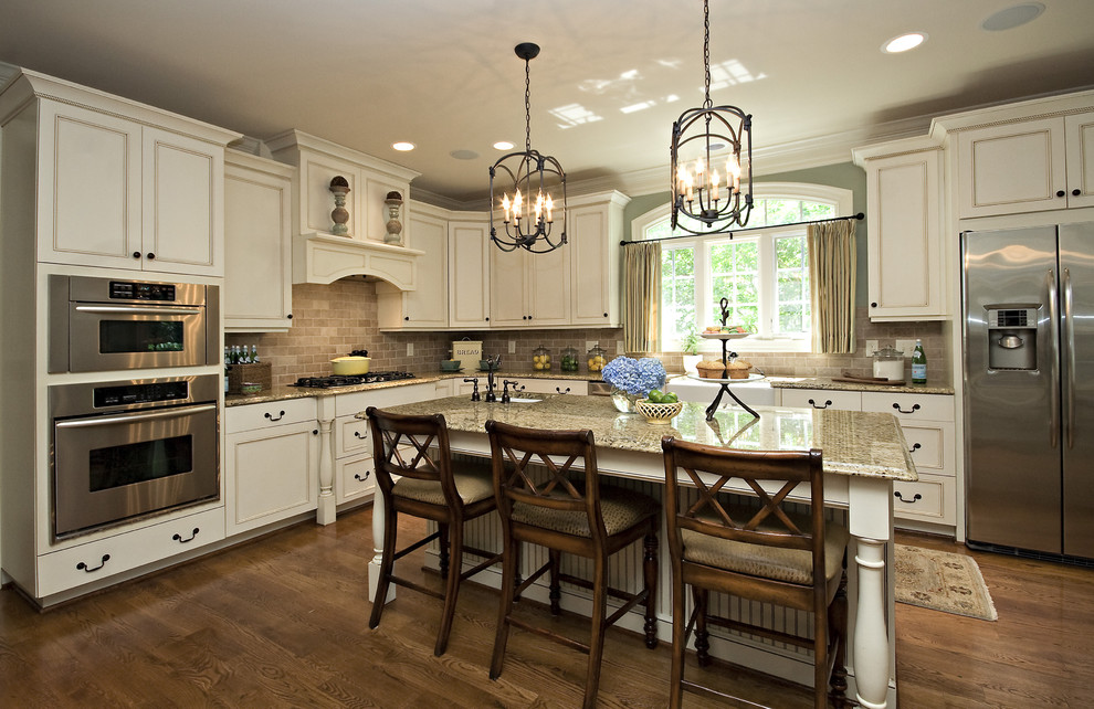 Elegant l-shaped kitchen photo in Raleigh with white cabinets, brown backsplash, stainless steel appliances and stone tile backsplash