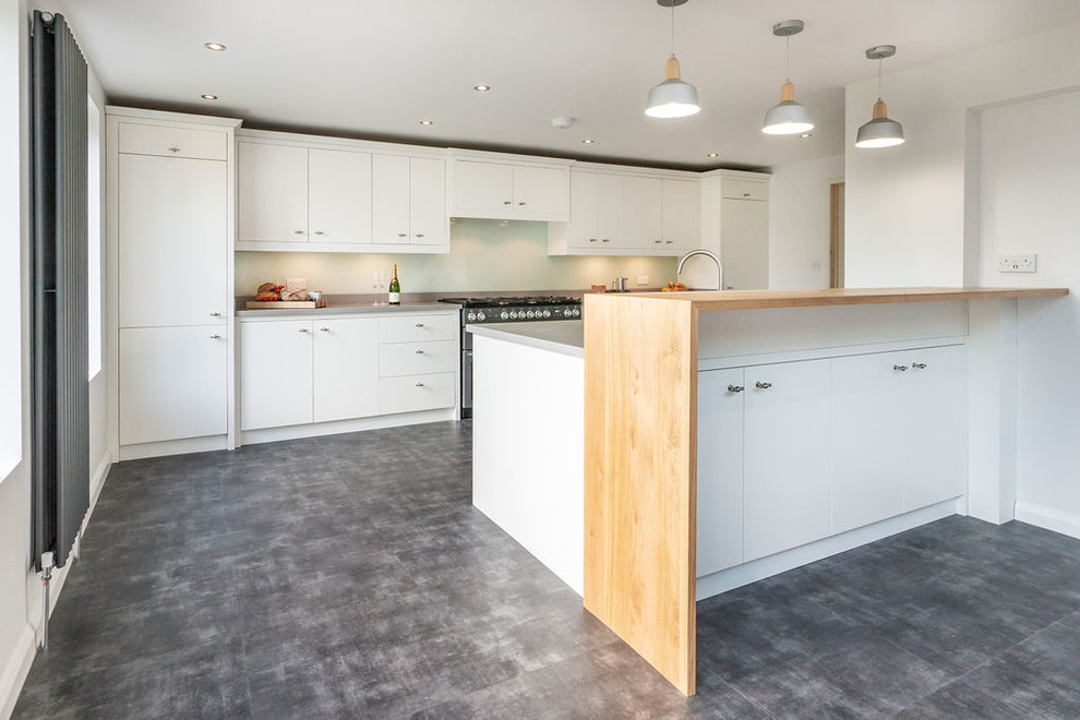 Modern kitchen/diner in Berkshire with flat-panel cabinets, glass sheet splashback, integrated appliances, an island, grey floors and grey worktops.