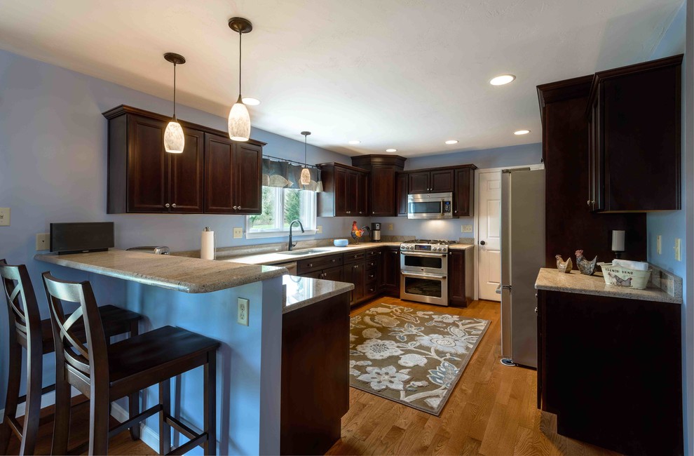 Mid-sized transitional u-shaped medium tone wood floor and brown floor enclosed kitchen photo in Other with an undermount sink, beaded inset cabinets, dark wood cabinets, granite countertops, stainless steel appliances and an island