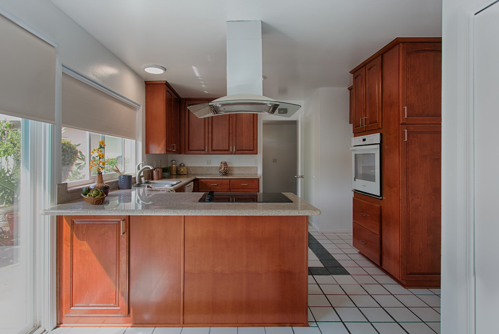 Medium sized contemporary u-shaped kitchen in Orange County with a double-bowl sink, raised-panel cabinets, medium wood cabinets, granite worktops and stainless steel appliances.