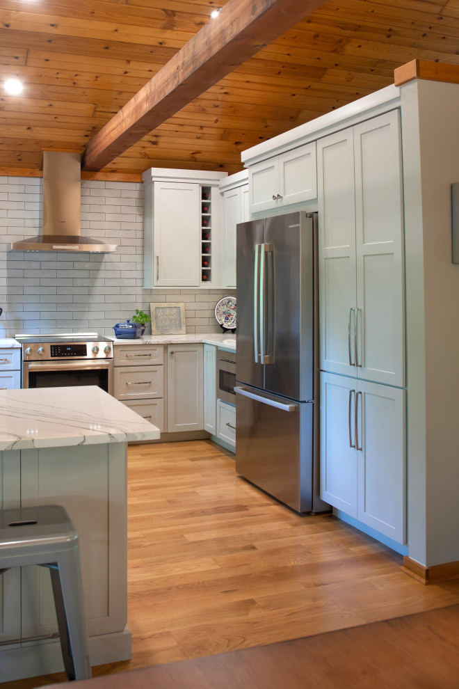 Klassisk inredning av ett avskilt, mellanstort vit vitt u-kök, med en undermonterad diskho, luckor med infälld panel, grå skåp, bänkskiva i kvarts, vitt stänkskydd, stänkskydd i porslinskakel, rostfria vitvaror, mellanmörkt trägolv, en halv köksö och brunt golv
