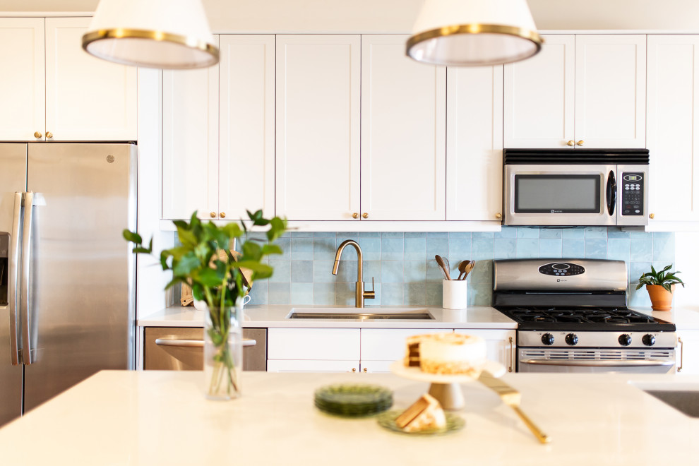 ワシントンD.C.にある低価格の中くらいなエクレクティックスタイルのおしゃれなアイランドキッチン (シングルシンク、シェーカースタイル扉のキャビネット、白いキャビネット、クオーツストーンカウンター、青いキッチンパネル、セラミックタイルのキッチンパネル、シルバーの調理設備、無垢フローリング、茶色い床、グレーのキッチンカウンター) の写真