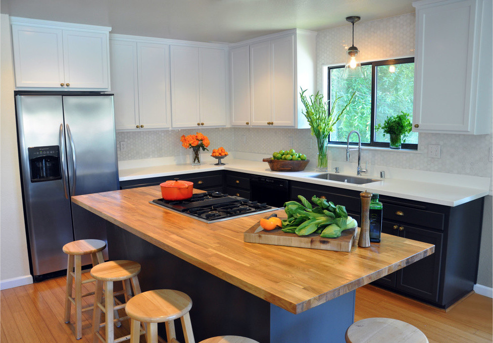 Mid-sized transitional l-shaped medium tone wood floor enclosed kitchen photo in San Francisco with an undermount sink, black cabinets, granite countertops, white backsplash, mosaic tile backsplash, stainless steel appliances, an island and recessed-panel cabinets