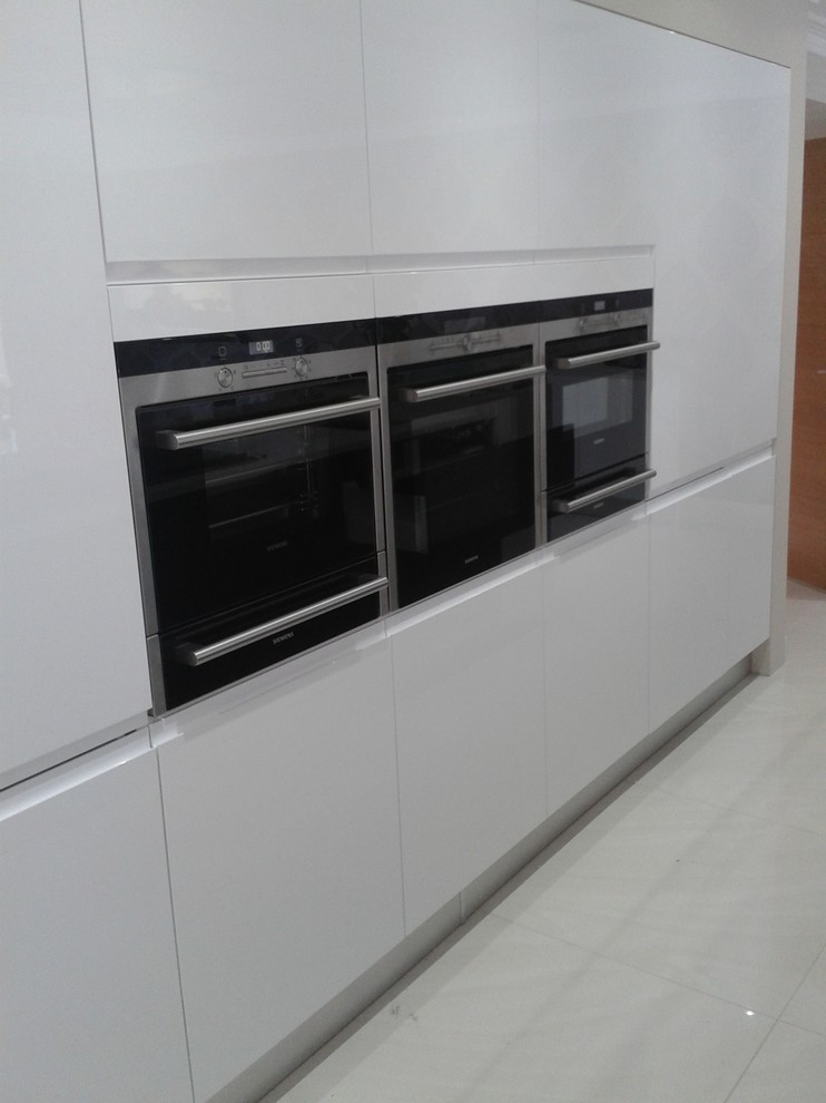 Foto på ett mellanstort funkis kök, med en integrerad diskho, släta luckor, vita skåp, bänkskiva i koppar, rostfria vitvaror, klinkergolv i porslin och en köksö