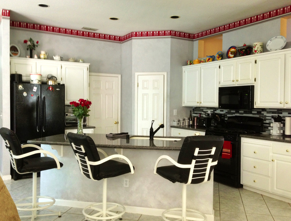 Inspiration för ett mellanstort vintage kök, med en undermonterad diskho, luckor med upphöjd panel, vita skåp, granitbänkskiva, flerfärgad stänkskydd, svarta vitvaror, klinkergolv i keramik och en köksö