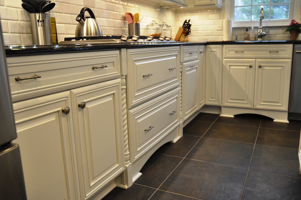 Inspiration for a mid-sized timeless l-shaped slate floor and black floor kitchen remodel in DC Metro with an undermount sink, raised-panel cabinets, white cabinets, granite countertops, white backsplash, stone tile backsplash, stainless steel appliances and an island