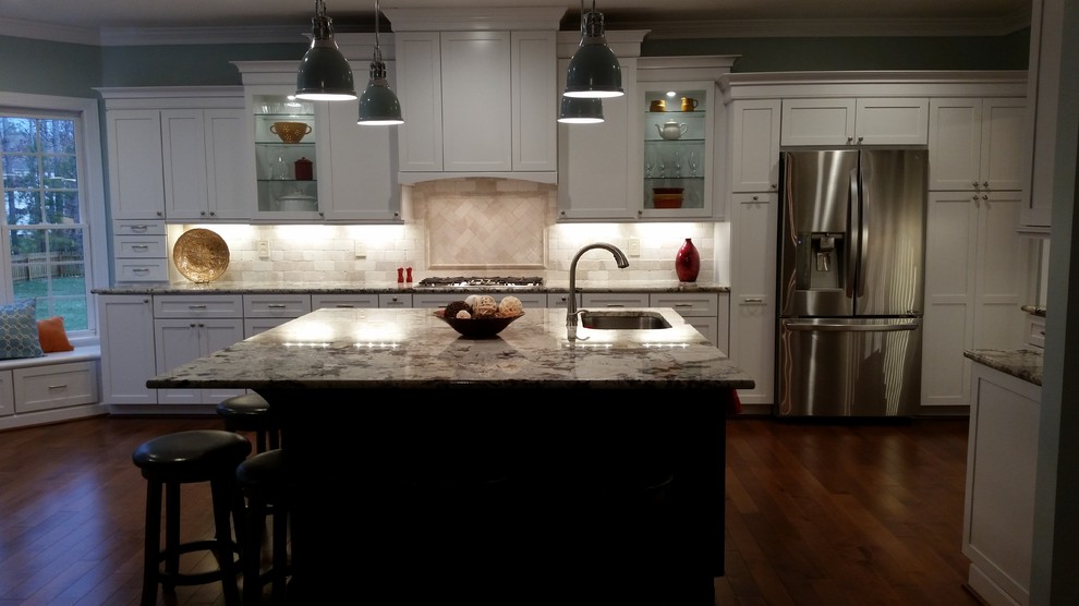 Huge transitional l-shaped medium tone wood floor open concept kitchen photo in Richmond with an undermount sink, recessed-panel cabinets, white cabinets, glass countertops, beige backsplash, subway tile backsplash, stainless steel appliances and an island