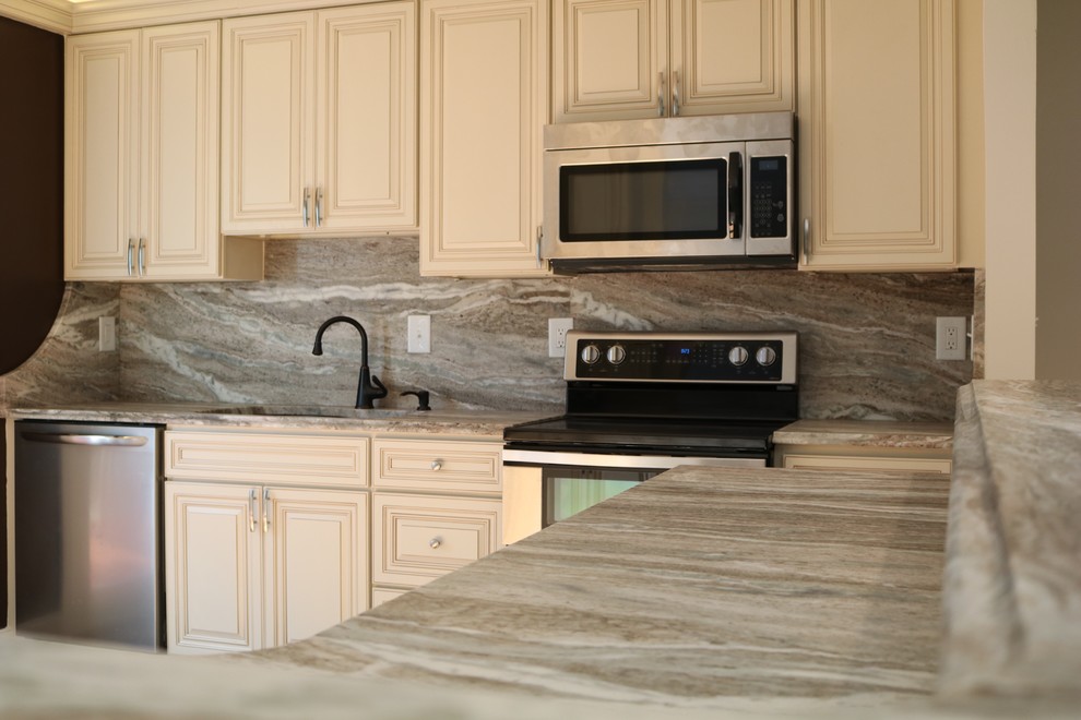 Mid-sized transitional l-shaped kitchen photo in DC Metro with an undermount sink, raised-panel cabinets, white cabinets, granite countertops, gray backsplash, stainless steel appliances and an island