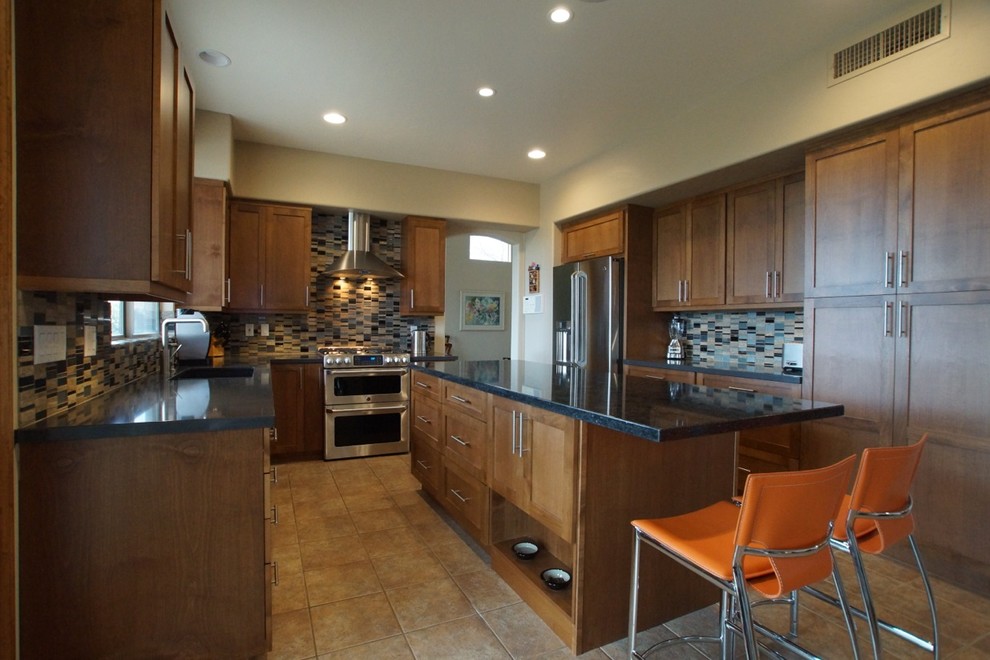 Eat-in kitchen - mid-sized contemporary galley ceramic tile eat-in kitchen idea in Phoenix with an undermount sink, shaker cabinets, medium tone wood cabinets, granite countertops, multicolored backsplash, glass tile backsplash, stainless steel appliances and an island