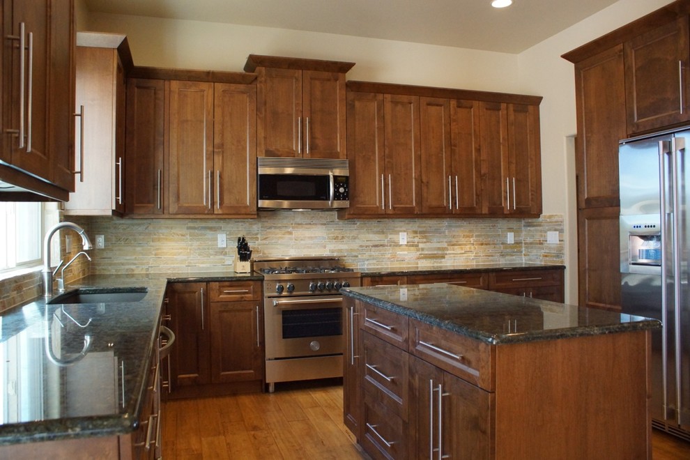 Klassisk inredning av ett mellanstort kök, med en undermonterad diskho, skåp i shakerstil, skåp i mellenmörkt trä, granitbänkskiva, beige stänkskydd, stänkskydd i stenkakel, rostfria vitvaror, mellanmörkt trägolv och en köksö