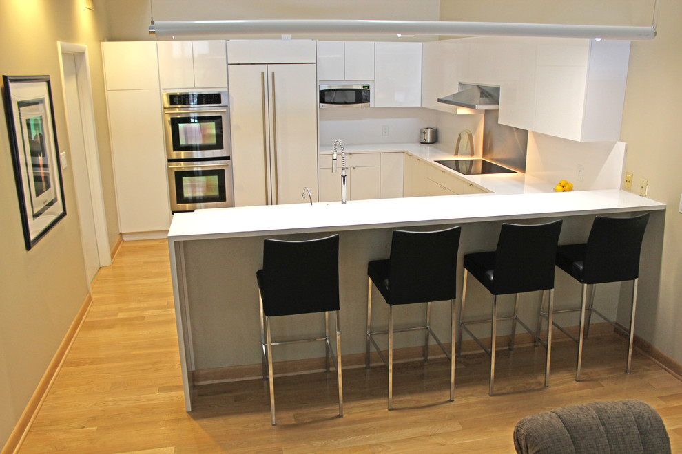 Bild på ett funkis kök, med en enkel diskho, släta luckor, vita skåp, bänkskiva i kvartsit, vitt stänkskydd, stänkskydd i sten, integrerade vitvaror och mellanmörkt trägolv