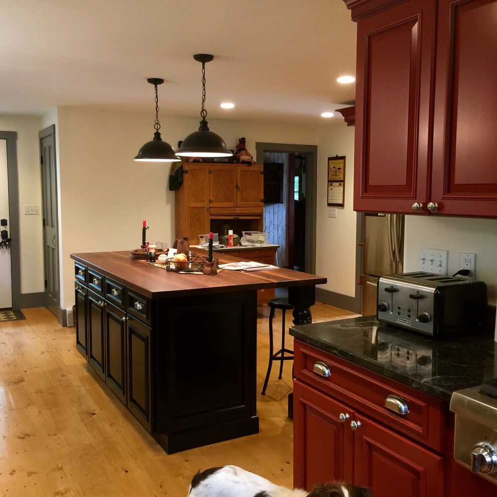 Große Landhaus Küche in U-Form mit Landhausspüle, profilierten Schrankfronten, roten Schränken, Mineralwerkstoff-Arbeitsplatte, Küchengeräten aus Edelstahl, hellem Holzboden und Kücheninsel in Boston