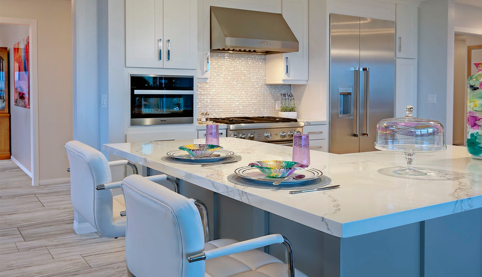 Medium sized modern u-shaped open plan kitchen in San Diego with a belfast sink, shaker cabinets, grey cabinets, engineered stone countertops, glass tiled splashback, stainless steel appliances, porcelain flooring, an island, grey floors and white worktops.