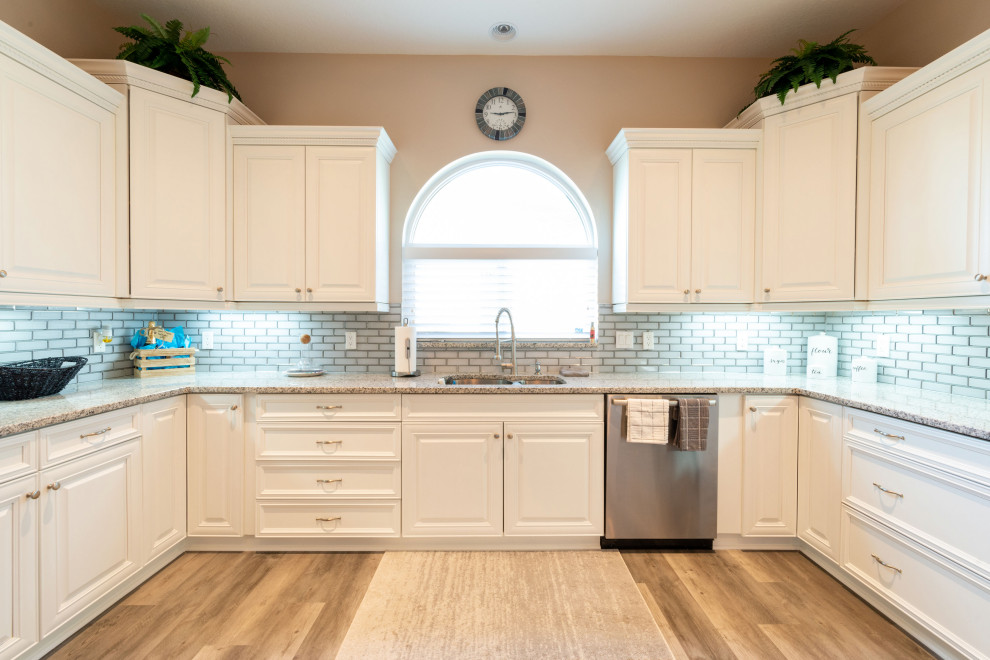 Example of a mid-sized transitional u-shaped vinyl floor and brown floor eat-in kitchen design in Other with a double-bowl sink, shaker cabinets, white cabinets, granite countertops, white backsplash, subway tile backsplash, stainless steel appliances, no island and multicolored countertops