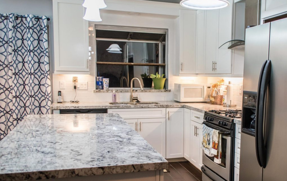 Kitchen - small transitional l-shaped porcelain tile and brown floor kitchen idea in Los Angeles with an undermount sink, shaker cabinets, white cabinets, granite countertops, white backsplash, subway tile backsplash, stainless steel appliances, an island and multicolored countertops