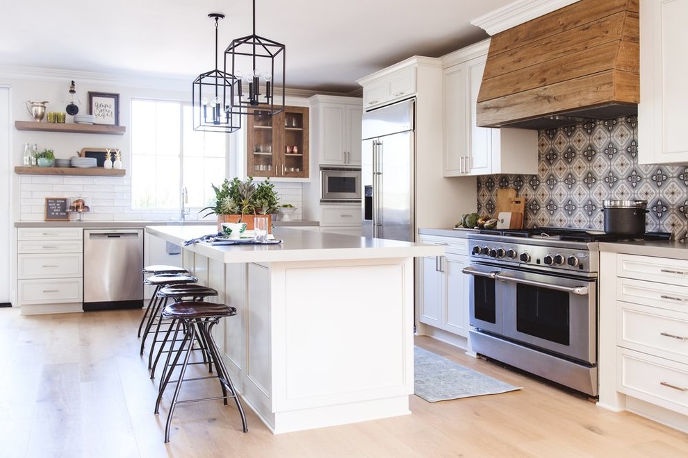Exempel på ett stort medelhavsstil grå grått kök, med en köksö, luckor med infälld panel, vita skåp, flerfärgad stänkskydd, rostfria vitvaror och ljust trägolv