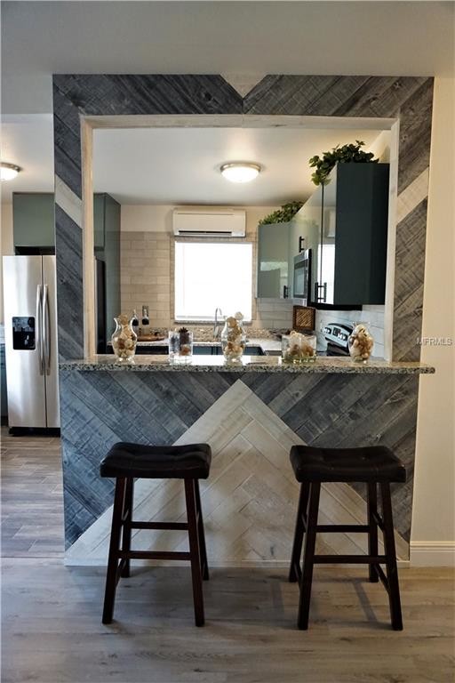 Example of a mid-sized minimalist l-shaped ceramic tile and gray floor eat-in kitchen design in Tampa with a double-bowl sink, flat-panel cabinets, turquoise cabinets, granite countertops, gray backsplash, ceramic backsplash, stainless steel appliances, a peninsula and gray countertops
