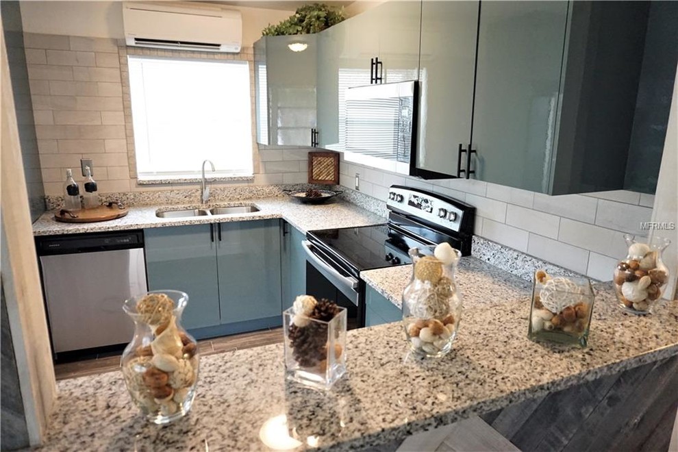 Eat-in kitchen - mid-sized modern l-shaped ceramic tile and gray floor eat-in kitchen idea in Tampa with a double-bowl sink, flat-panel cabinets, turquoise cabinets, granite countertops, gray backsplash, ceramic backsplash, stainless steel appliances, a peninsula and gray countertops