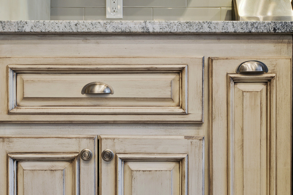 Inredning av ett klassiskt mellanstort flerfärgad flerfärgat kök, med en undermonterad diskho, luckor med upphöjd panel, skåp i slitet trä, granitbänkskiva, grått stänkskydd, stänkskydd i porslinskakel, rostfria vitvaror, klinkergolv i porslin, en köksö och grått golv
