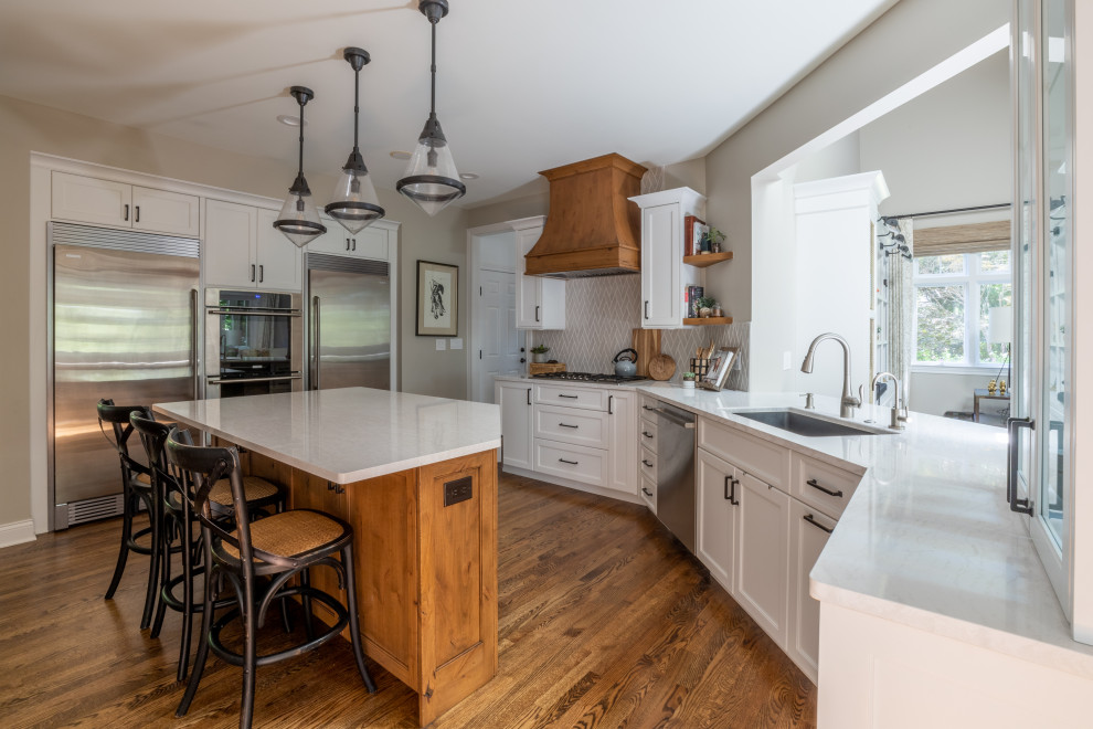 Inspiration for a huge transitional u-shaped medium tone wood floor, brown floor and wood ceiling eat-in kitchen remodel in Detroit with an undermount sink, white cabinets, beige backsplash, stainless steel appliances, an island, white countertops, flat-panel cabinets, quartz countertops and porcelain backsplash
