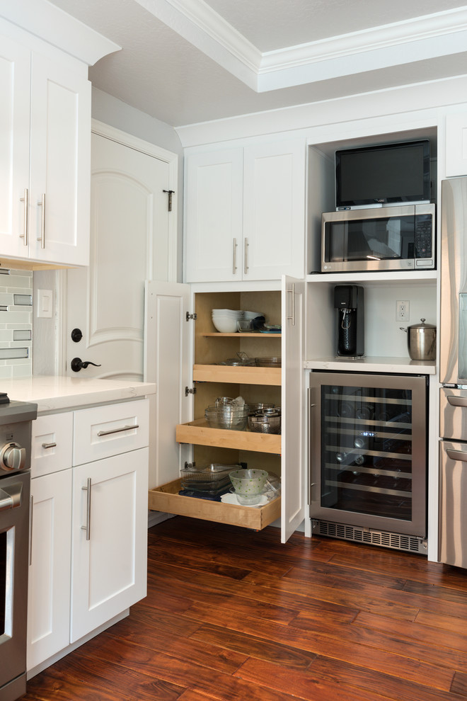 Foto de cocina clásica renovada con puertas de armario blancas, salpicadero blanco y una isla