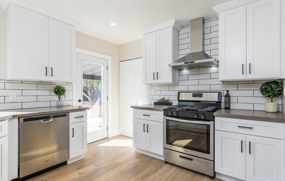 Inspiration for a medium sized classic galley enclosed kitchen in Los Angeles with a submerged sink, shaker cabinets, white cabinets, engineered stone countertops, white splashback, metro tiled splashback, stainless steel appliances, medium hardwood flooring, no island, brown floors and grey worktops.