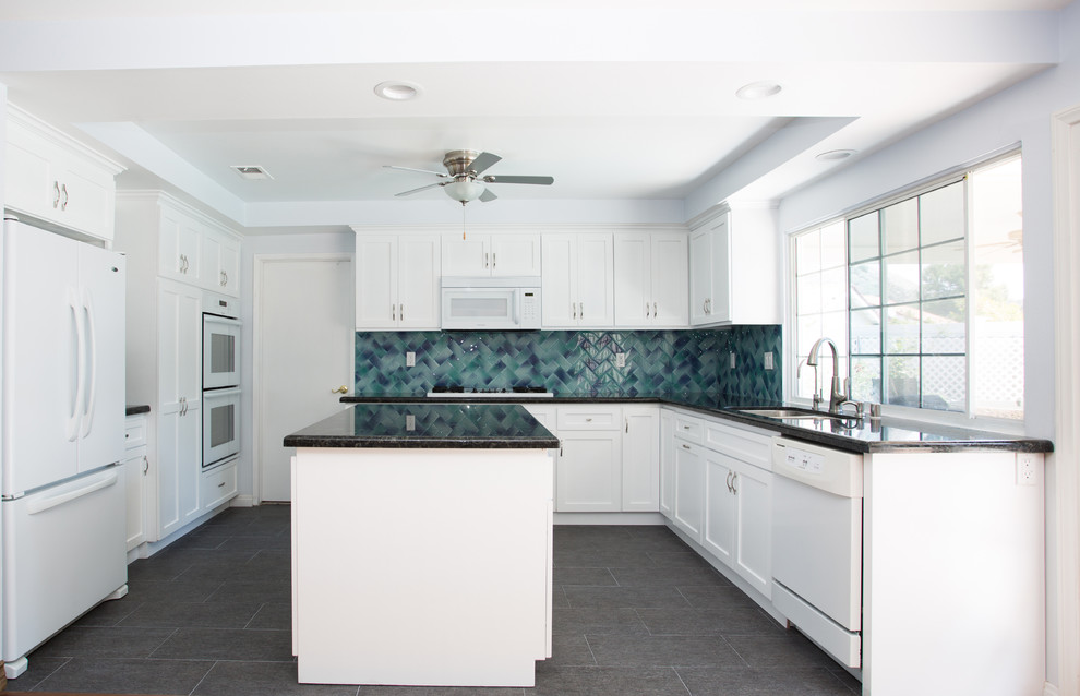 Enclosed kitchen - mid-sized contemporary u-shaped porcelain tile and gray floor enclosed kitchen idea in Los Angeles with a double-bowl sink, shaker cabinets, white cabinets, granite countertops, blue backsplash, glass tile backsplash, white appliances and an island