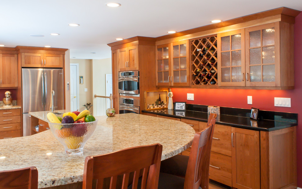Elegant l-shaped eat-in kitchen photo in Boston with an undermount sink, recessed-panel cabinets, medium tone wood cabinets, granite countertops, red backsplash and stainless steel appliances