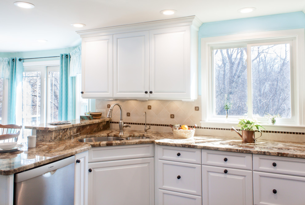 Eat-in kitchen - traditional u-shaped eat-in kitchen idea in Boston with an undermount sink, raised-panel cabinets, white cabinets, granite countertops, beige backsplash, ceramic backsplash and stainless steel appliances