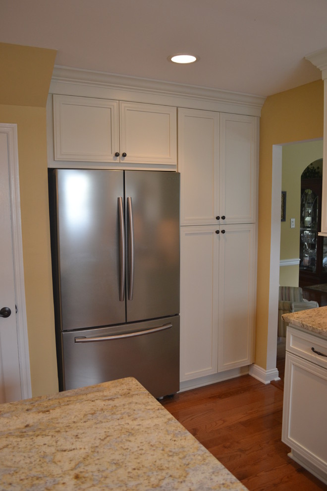 Example of a large classic l-shaped medium tone wood floor kitchen pantry design in Philadelphia with an undermount sink, flat-panel cabinets, white cabinets, granite countertops, beige backsplash, ceramic backsplash, stainless steel appliances and an island