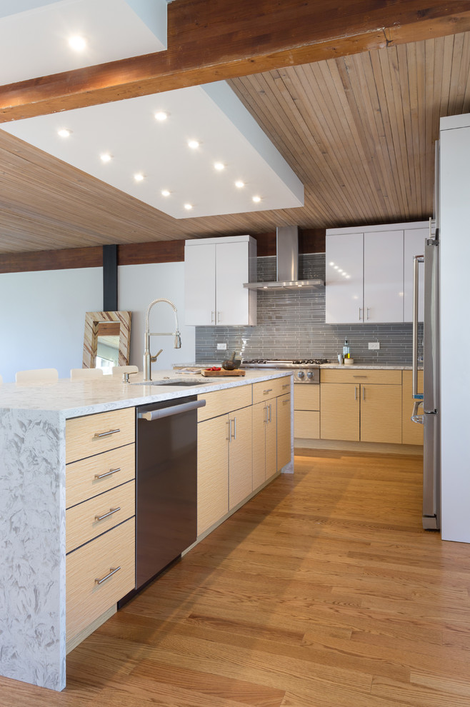 Example of a large minimalist l-shaped medium tone wood floor open concept kitchen design in Chicago with flat-panel cabinets, white cabinets, marble countertops, gray backsplash, stainless steel appliances, an island, subway tile backsplash and an undermount sink