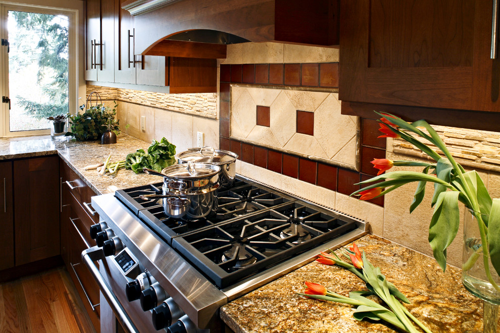 Inredning av ett modernt kök, med en undermonterad diskho, skåp i shakerstil, bruna skåp, granitbänkskiva, beige stänkskydd, stänkskydd i glaskakel, rostfria vitvaror och ljust trägolv