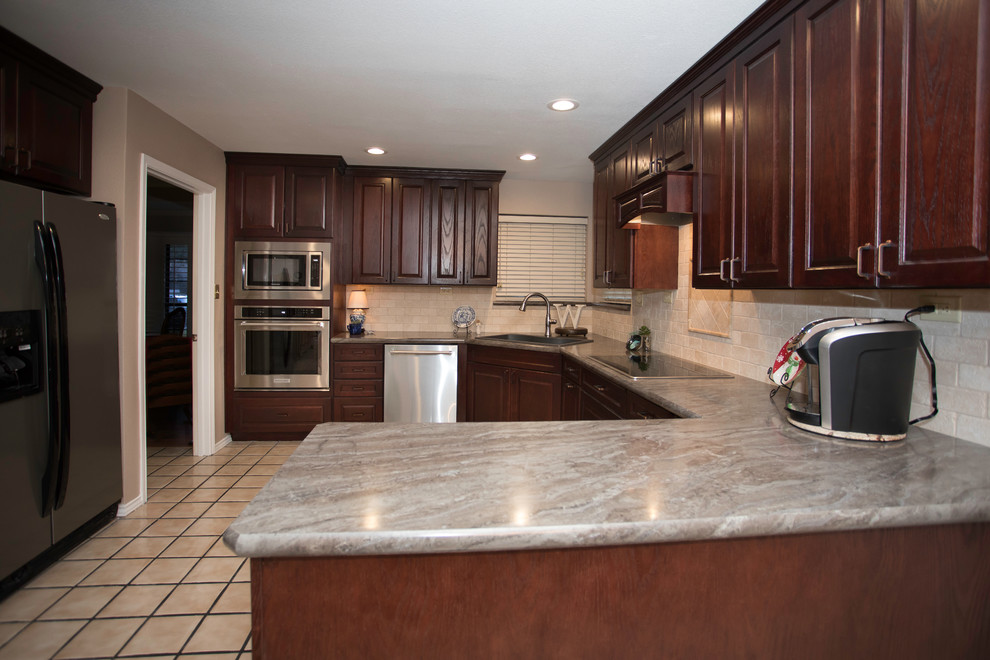 Example of a mid-sized classic u-shaped porcelain tile eat-in kitchen design in Dallas with a double-bowl sink, raised-panel cabinets, dark wood cabinets, laminate countertops, beige backsplash, stone tile backsplash, stainless steel appliances and no island