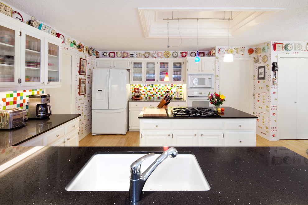 Bild på ett mellanstort eklektiskt svart svart kök, med en enkel diskho, luckor med upphöjd panel, vita skåp, granitbänkskiva, flerfärgad stänkskydd, stänkskydd i mosaik, vita vitvaror, bambugolv, brunt golv och flera köksöar