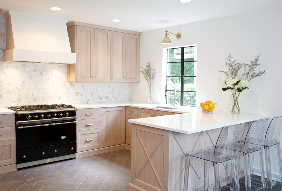 This is an example of a medium sized traditional u-shaped open plan kitchen in Atlanta with shaker cabinets, light wood cabinets, white splashback, a breakfast bar, a submerged sink, engineered stone countertops, marble splashback, black appliances, porcelain flooring, brown floors and white worktops.