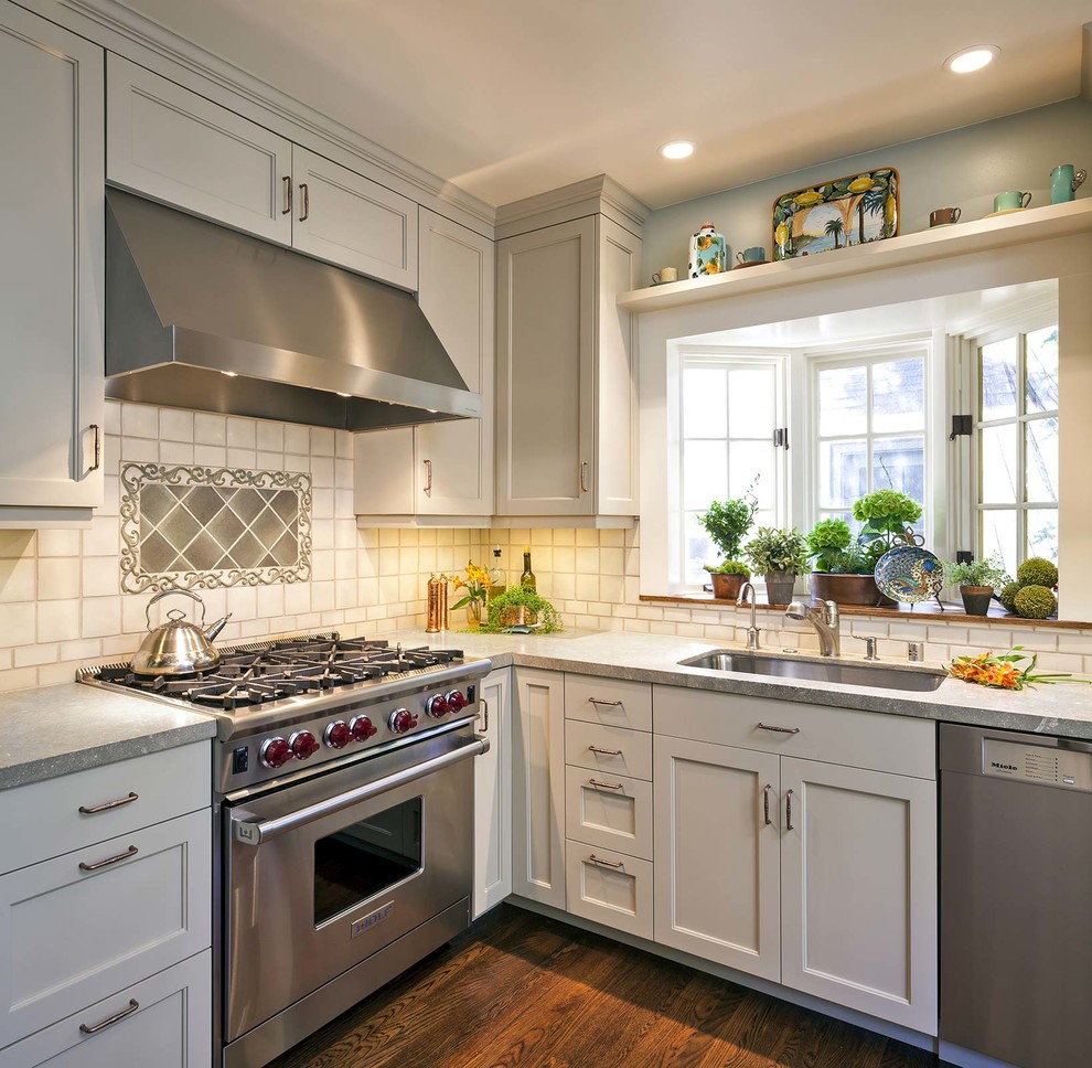 Classic l-shaped kitchen in San Francisco with a submerged sink, shaker cabinets, white cabinets, white splashback, stainless steel appliances and dark hardwood flooring.