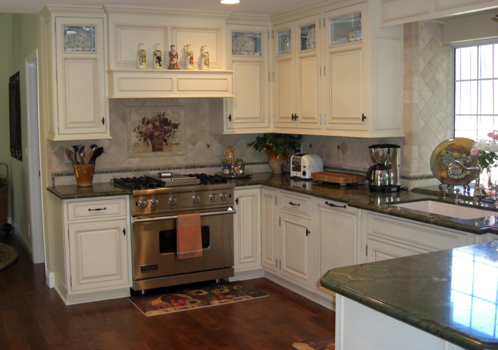 Example of a large classic u-shaped dark wood floor enclosed kitchen design in San Francisco with a drop-in sink, raised-panel cabinets, white cabinets, multicolored backsplash, stone tile backsplash and stainless steel appliances