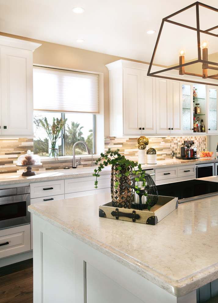 Inspiration for a large transitional single-wall laminate floor eat-in kitchen remodel in Phoenix with an undermount sink, raised-panel cabinets, white cabinets, quartz countertops, beige backsplash, mosaic tile backsplash, paneled appliances and an island