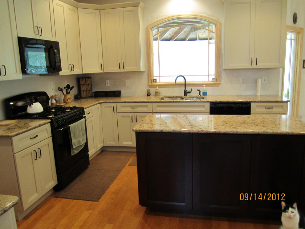 Inspiration for a mid-sized timeless l-shaped light wood floor eat-in kitchen remodel in Cleveland with an undermount sink, recessed-panel cabinets, white cabinets, granite countertops, black appliances and an island