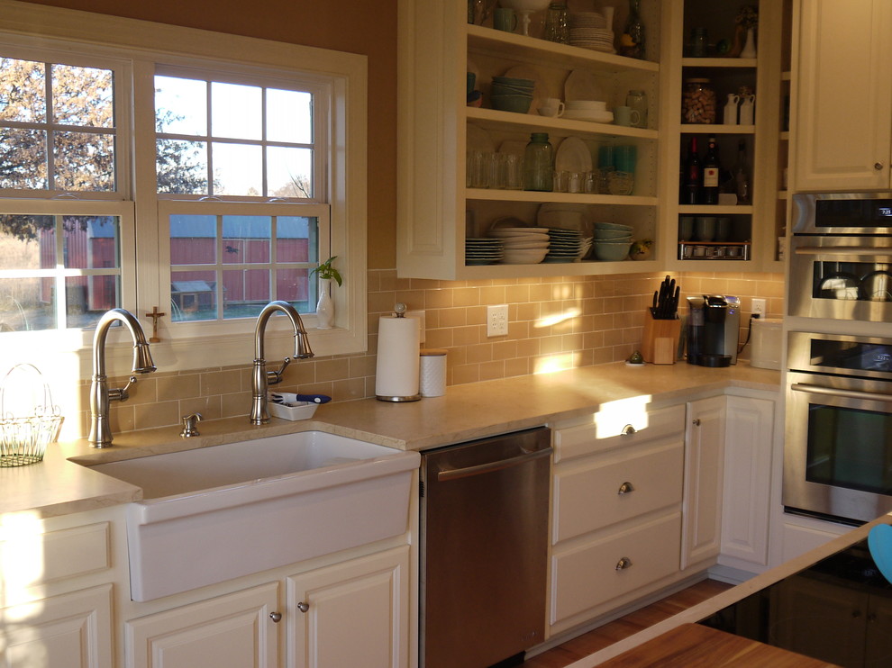 Lantlig inredning av ett mellanstort kök, med en rustik diskho, öppna hyllor, vita skåp, marmorbänkskiva, beige stänkskydd, stänkskydd i keramik, rostfria vitvaror, ljust trägolv och en köksö