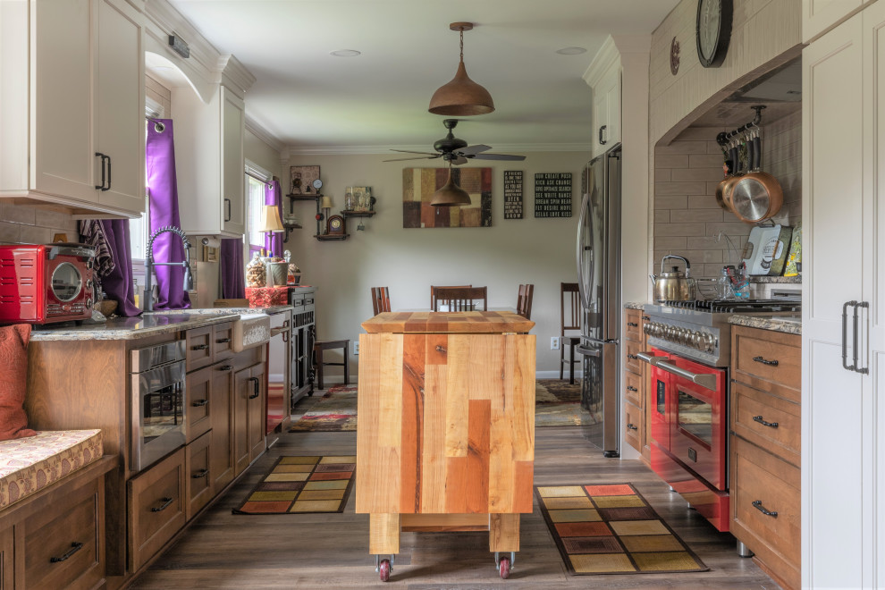 Inspiration for a mid-sized eclectic galley vinyl floor and gray floor eat-in kitchen remodel in Detroit with a farmhouse sink, colored appliances, recessed-panel cabinets, beige backsplash, subway tile backsplash, an island, brown cabinets, quartz countertops and gray countertops
