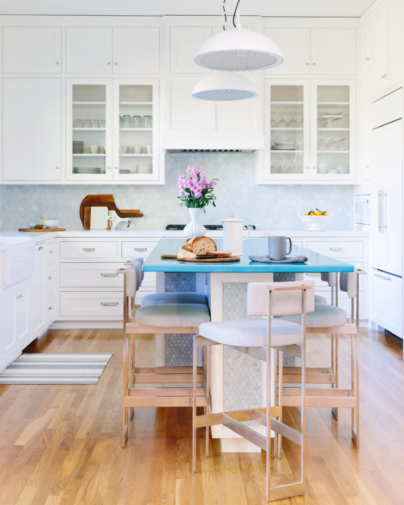 This is an example of a large contemporary u-shaped kitchen in San Francisco with a belfast sink, shaker cabinets, white cabinets, composite countertops, grey splashback, marble splashback, integrated appliances, medium hardwood flooring, an island, turquoise worktops and brown floors.