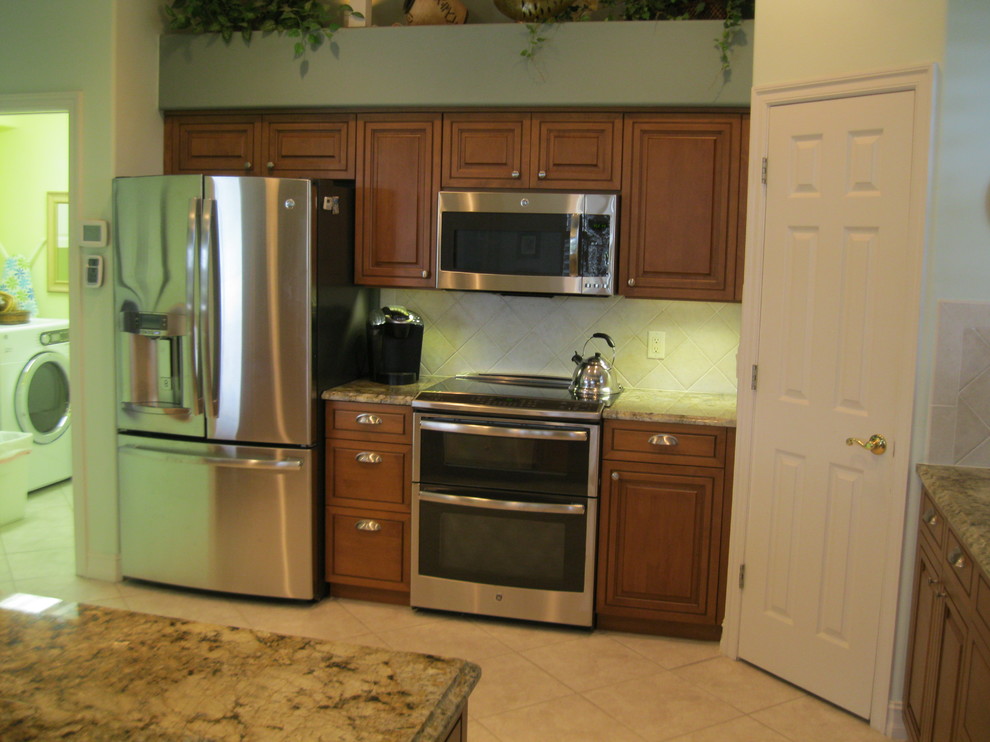 Exempel på ett avskilt, mellanstort klassiskt l-kök, med en undermonterad diskho, luckor med upphöjd panel, skåp i mellenmörkt trä, granitbänkskiva, rostfria vitvaror, klinkergolv i keramik, en köksö, beige stänkskydd och stänkskydd i stenkakel